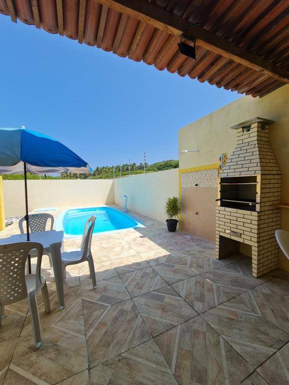 eine Terrasse mit einem Grill im Freien und einem Pool in der Unterkunft Chalés Sons do Mar in Barra do Cunhau