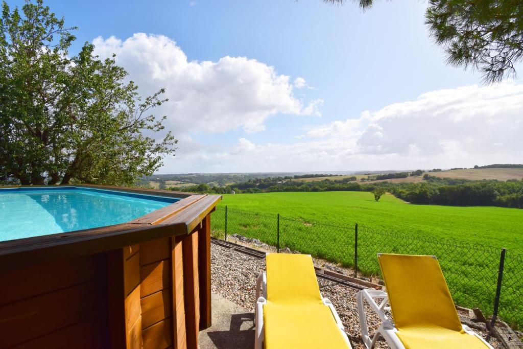 een zwembad met stoelen en uitzicht op een veld bij Ancienne ferme restaurée à Perville, Tarn-et-Garonne in Perville