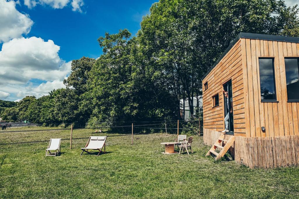 Cabaña de madera con sillas, mesa y sillas en Tiny House Centre équestre - 35 mins de Paris, en Chambly