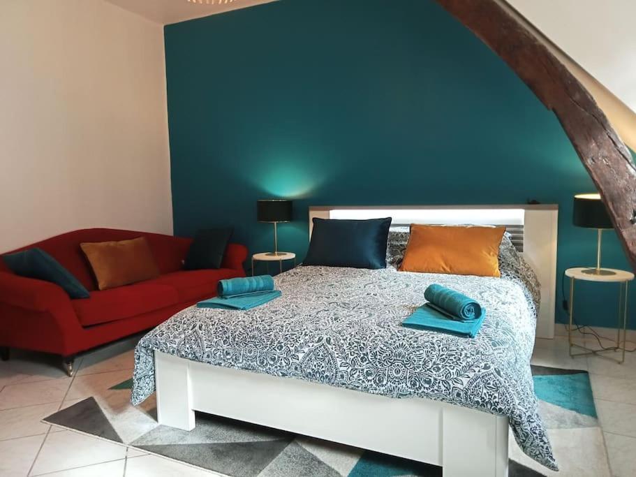 een slaapkamer met een bed en een rode bank bij Splendide Moulins in Moulins