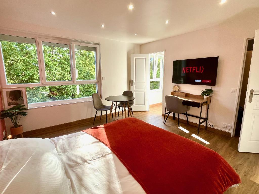 een slaapkamer met een bed, een tafel en een bureau bij Charmant studio + parking privé in Caen