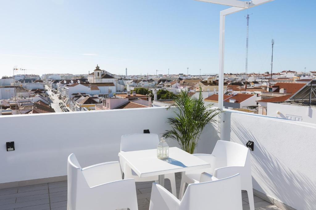 Villa Marquez Apartments في فيلا ريال دي سانتو انطونيو: بلكونه بيضاء مع طاوله وكراسي بيضاء