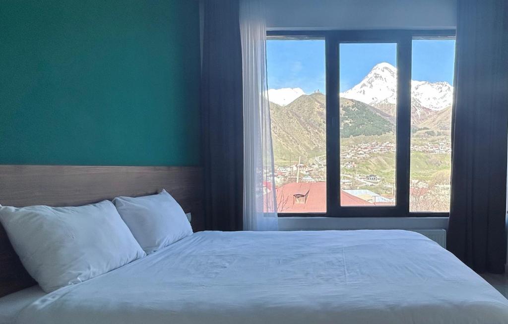 a bedroom with a bed and a window with mountains at Shushabandi Kazbegi in Kazbegi