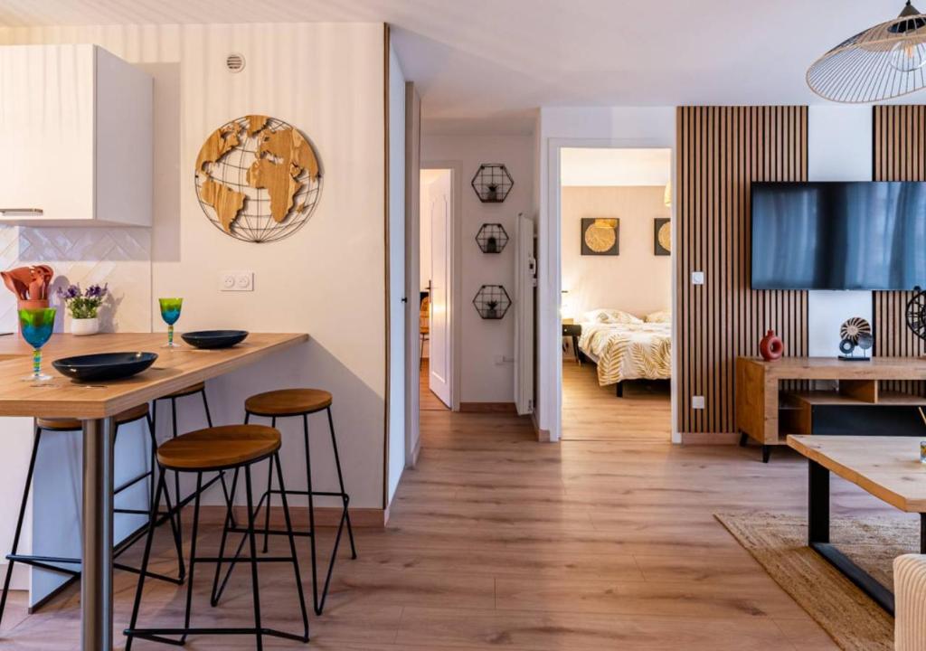 a kitchen and living room with a table and stools at Le Carrousel Avec Parking Privé in Dijon