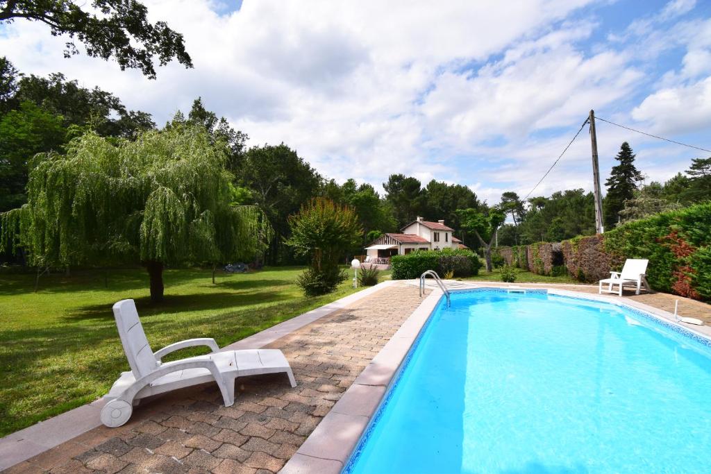 einen Pool mit zwei Liegestühlen neben einem Haus in der Unterkunft Ancienne gare rénovée - Clévacances 2 Clés in Réaup