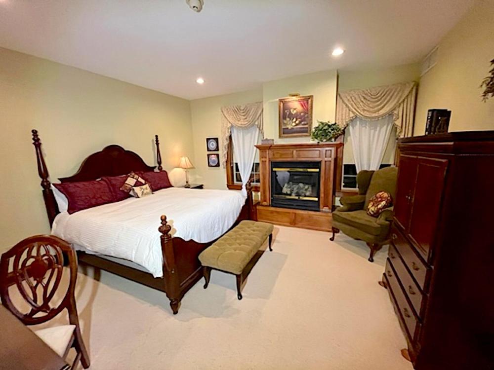 een slaapkamer met een groot bed en een open haard bij The Port Hotel in Port Washington