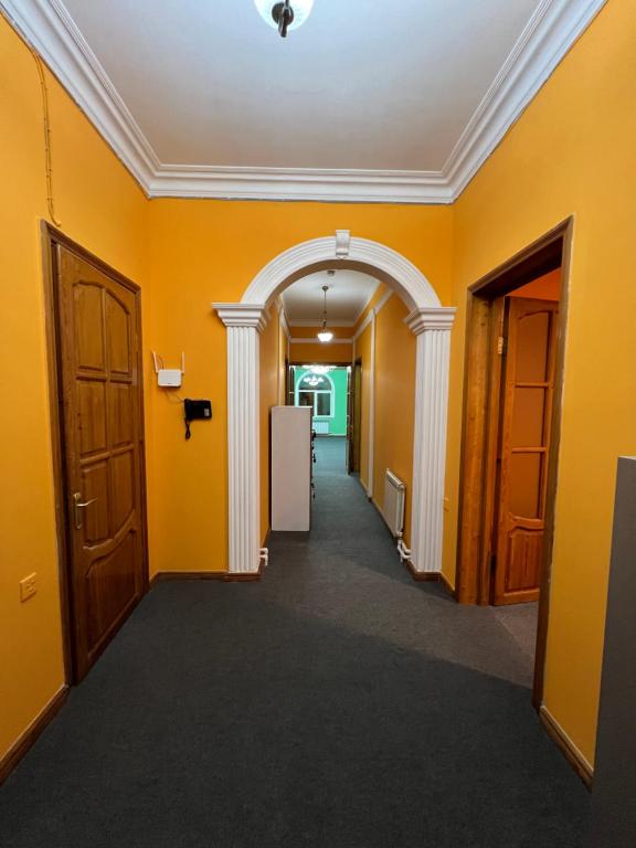 an empty hallway with yellow walls and an archway at Mexx Hostel in Baku