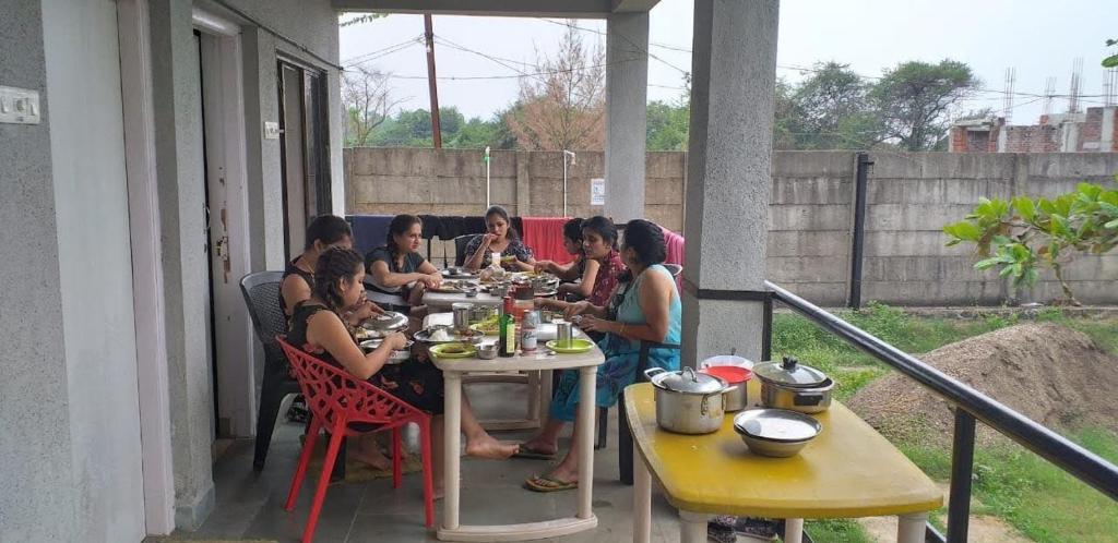 Eine Gruppe von Menschen, die an einem Tisch sitzen und Essen essen. in der Unterkunft SAMARA SEAVIEW in Alībāg