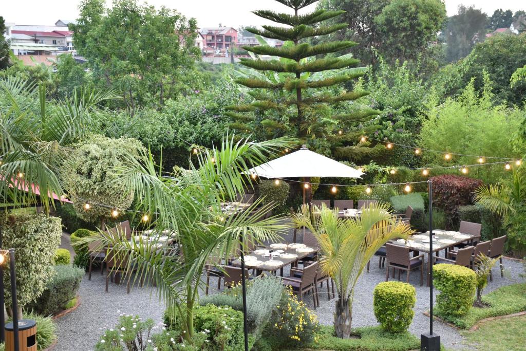 San Cristobal Boutique Hotel - Ivato Airport في أنتاناناريفو: حديقة بها طاولات وشجرة اناناس بها انوار