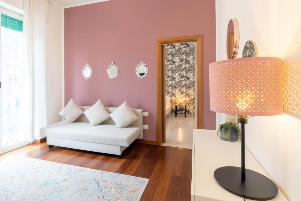 a living room with a white couch and a pink wall at Duomo - Citylife Pink Vintage APT center Milan in Milan