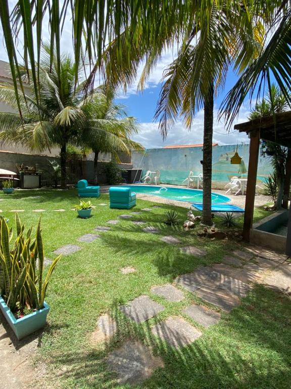 a backyard with a swimming pool with palm trees at Casa de Praia Suítes in Saquarema
