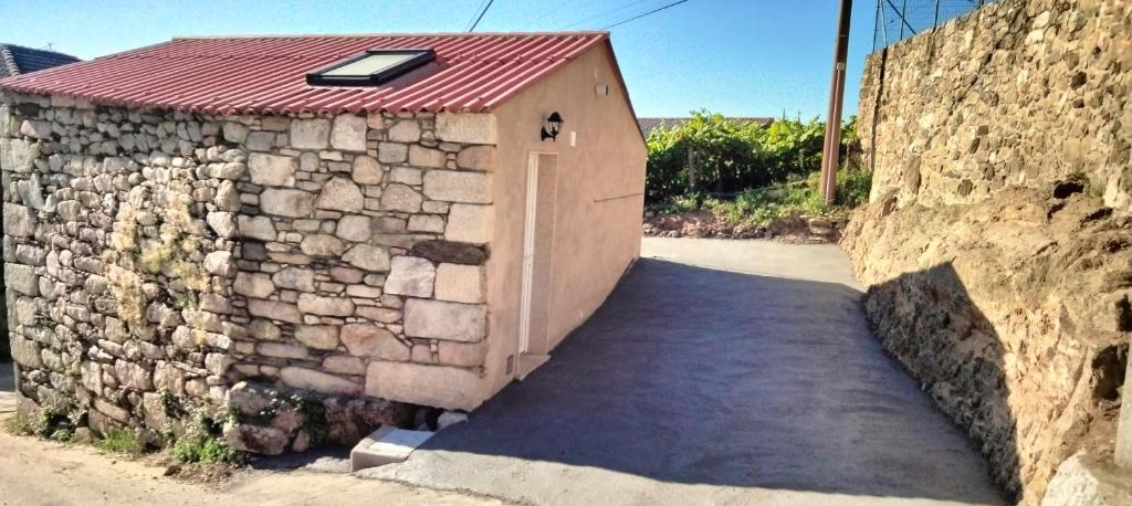 un pequeño edificio con techo rojo en una pared de piedra en Jacuzzi Barcala en Valga