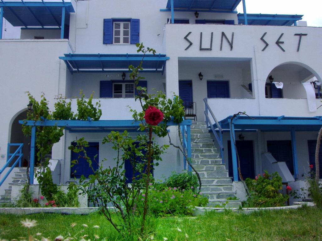 una casa blanca con adornos azules y una flor roja en Sunset, en Agios Prokopios