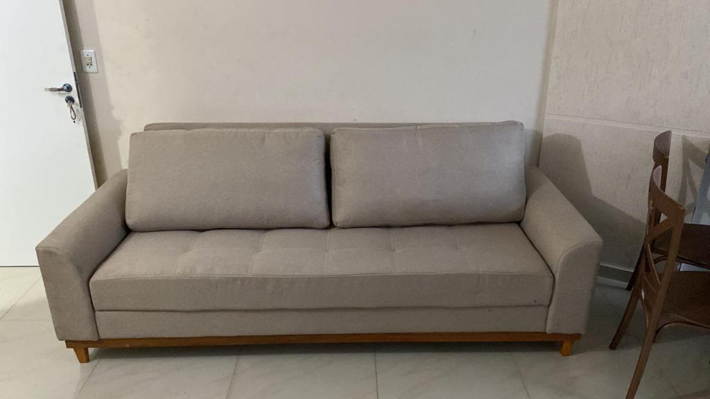 um sofá sentado numa sala ao lado de uma porta em Quarto e Sala Beira Mar Maceió em Maceió