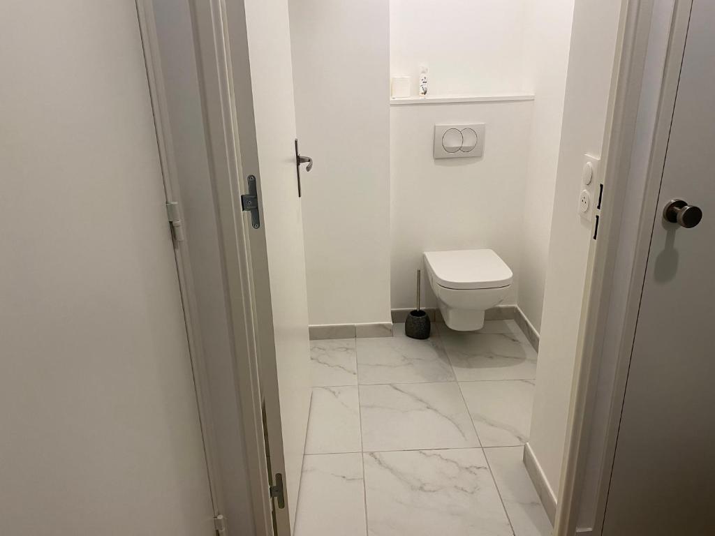 een badkamer met een toilet en een witte tegelvloer bij Chez Alice in Bezons
