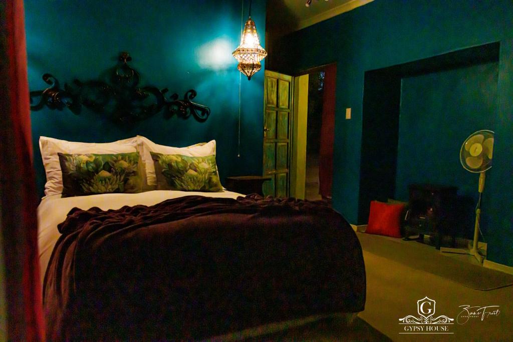 Gypsy Guest House Clarens في كلارينس: غرفة نوم بسرير مع جدار ازرق