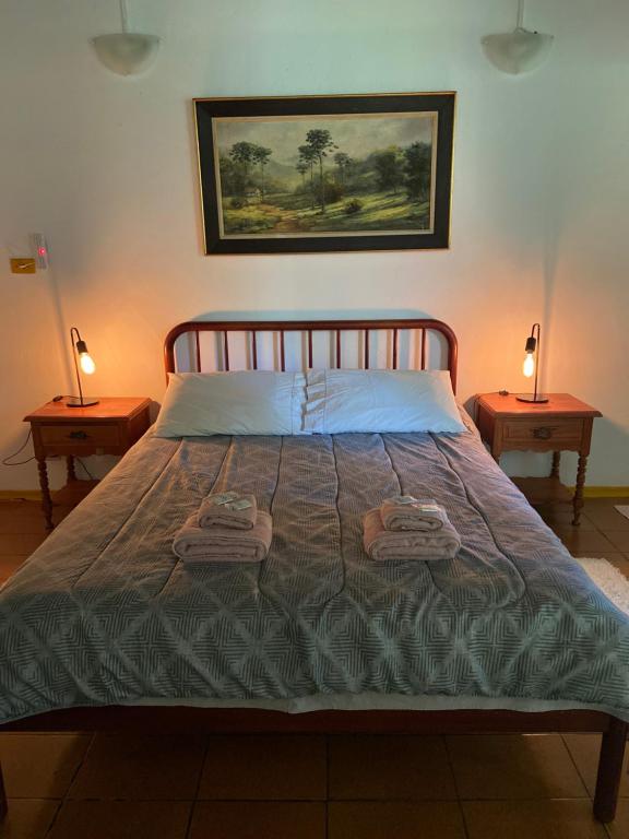 a bedroom with a bed with two lamps on two tables at Chalés SFX in São Francisco Xavier