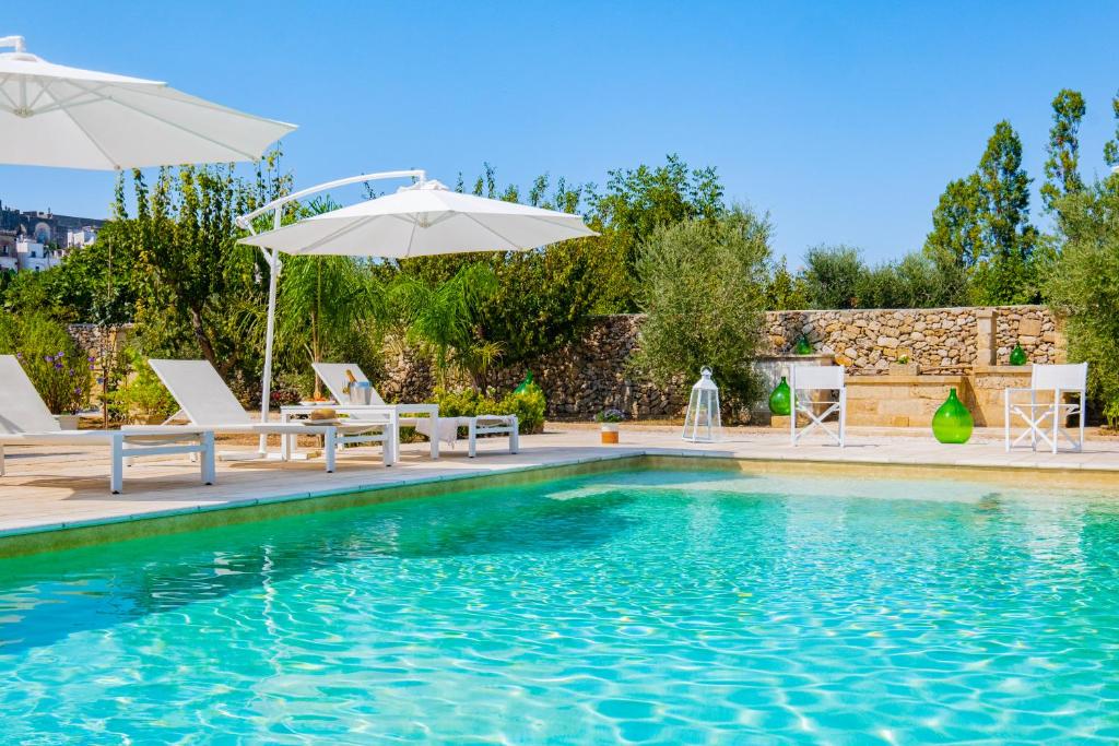 - une piscine avec des chaises et un parasol dans l'établissement Villa VentoSolare Luxury - Specchia, à Specchia