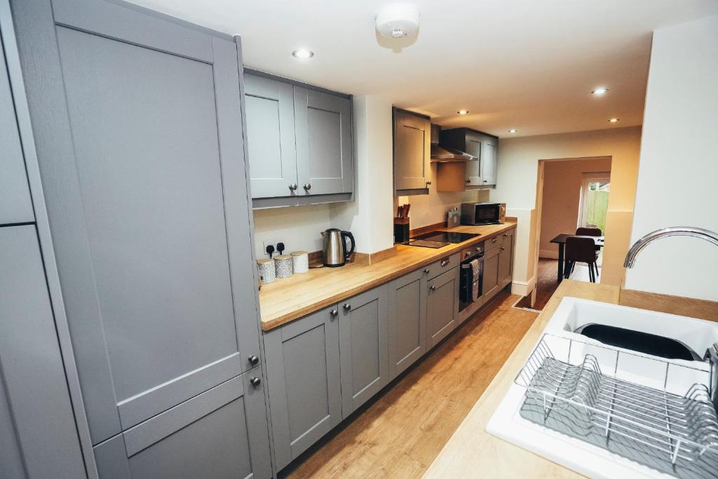 a kitchen with white cabinets and a counter top at Cottages in Derbyshire, King Street Cottage in Duffield