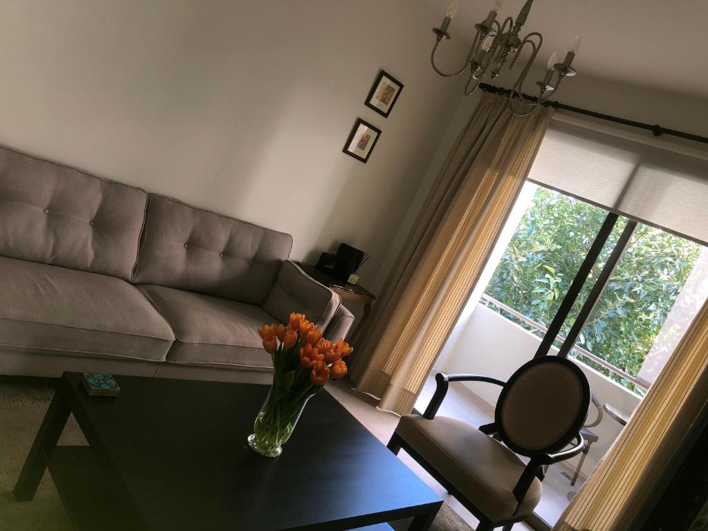 uma sala de estar com um sofá e um vaso de flores sobre uma mesa em T&L Apartments Germasogia em Limassol