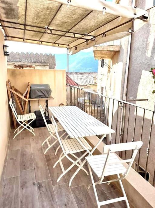 uma varanda com uma mesa e cadeiras. em Maison de village à 10 min d'Ile Rousse em Santa-Reparata-di-Balagna
