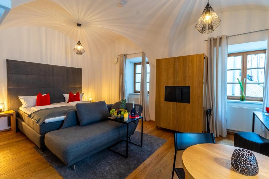 a bedroom with a bed and a couch and a table at BARONHAUS Aparthotel & Suites in Passau