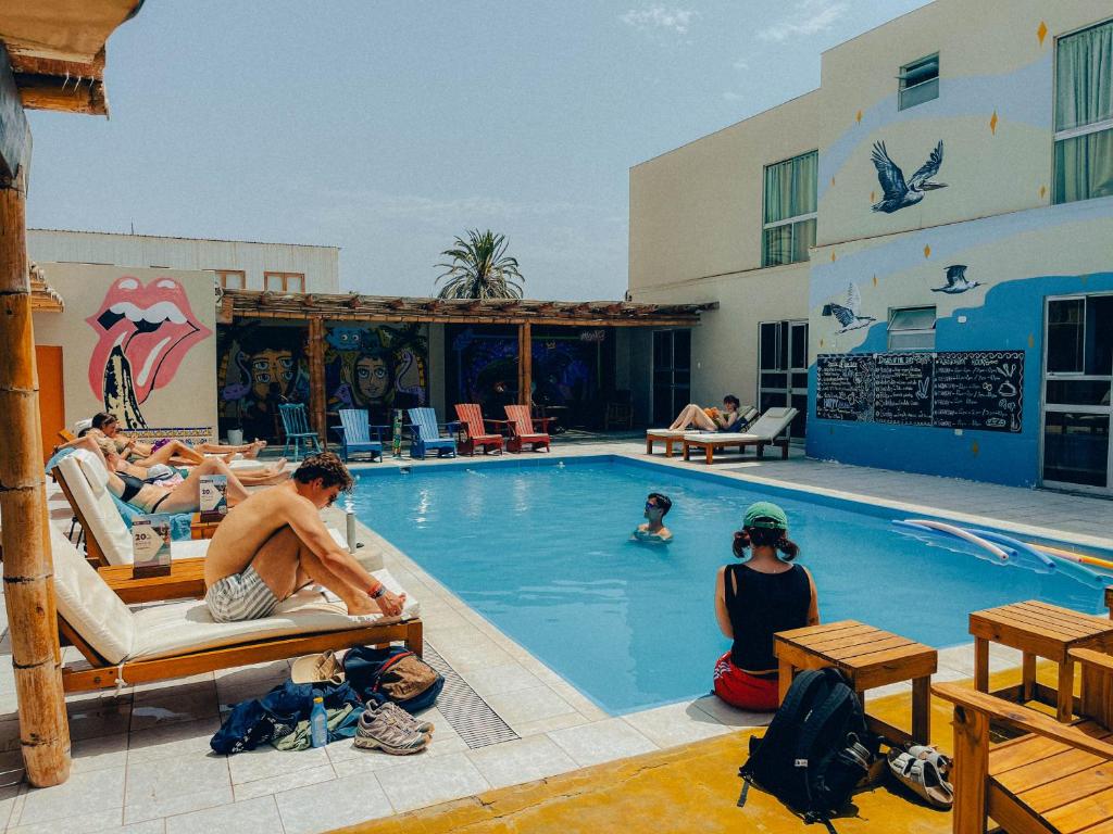 un groupe de personnes assises dans une piscine dans l'établissement Viajero-Kokopelli Paracas Hostel, à Paracas