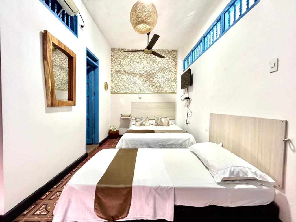 two beds in a room with white walls at Hotel Kasaya Real in Santa Marta