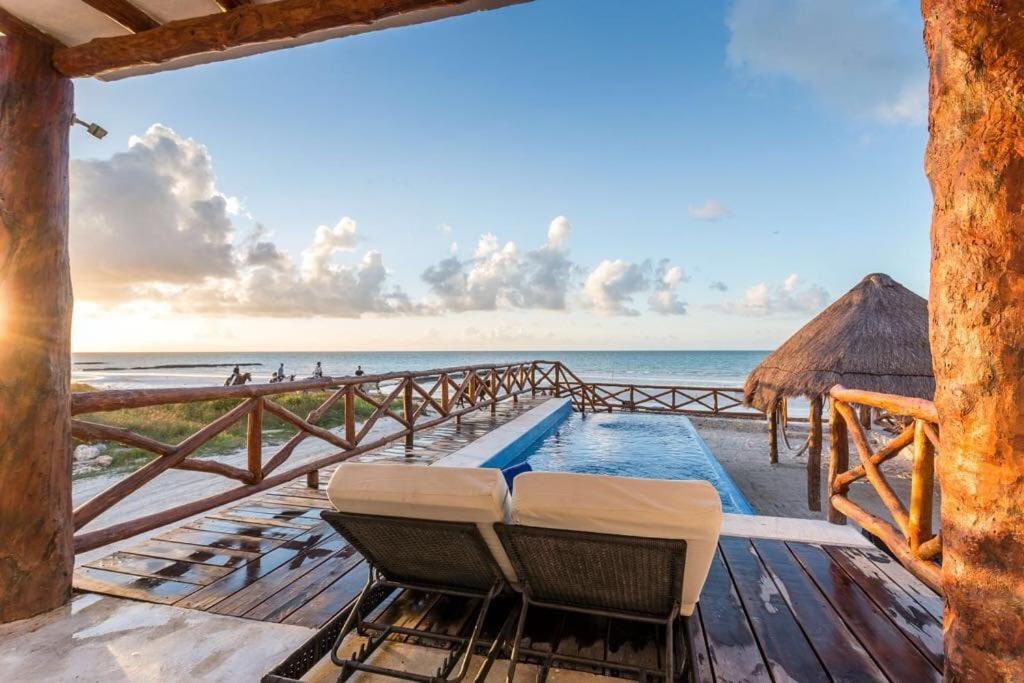 a deck with chairs and a swimming pool on the beach at Casa Libelula Beachfront House in Holbox Island