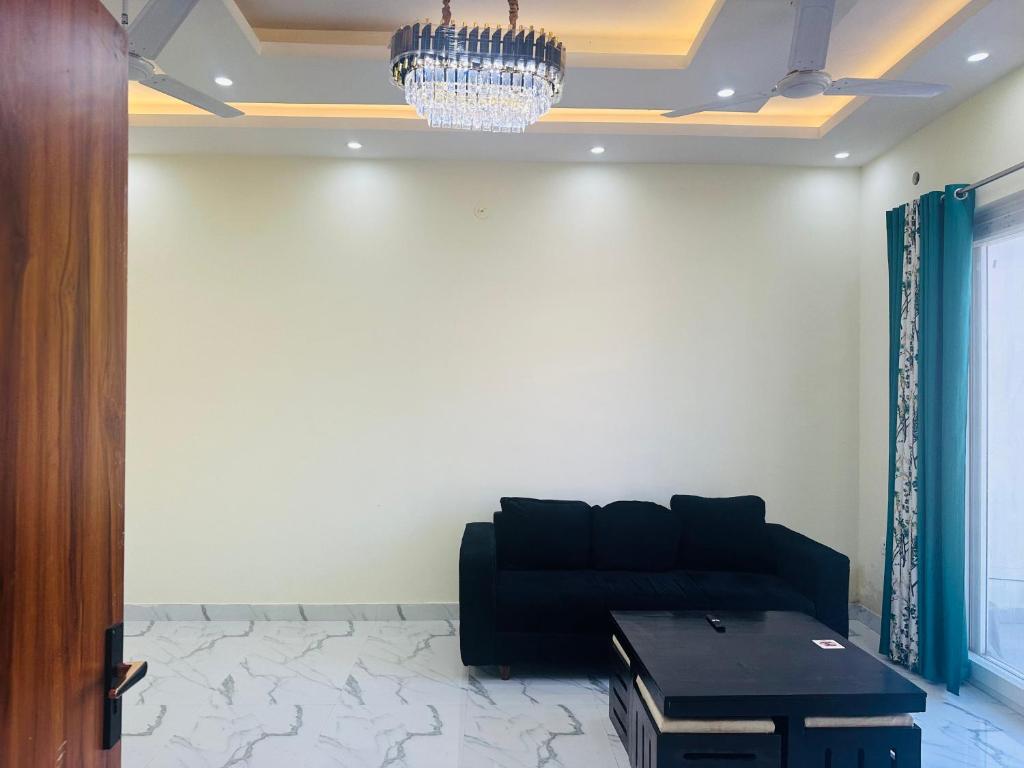 sala de estar con sofá negro y lámpara de araña en Spacious Villa in Dehradun en Dehradun
