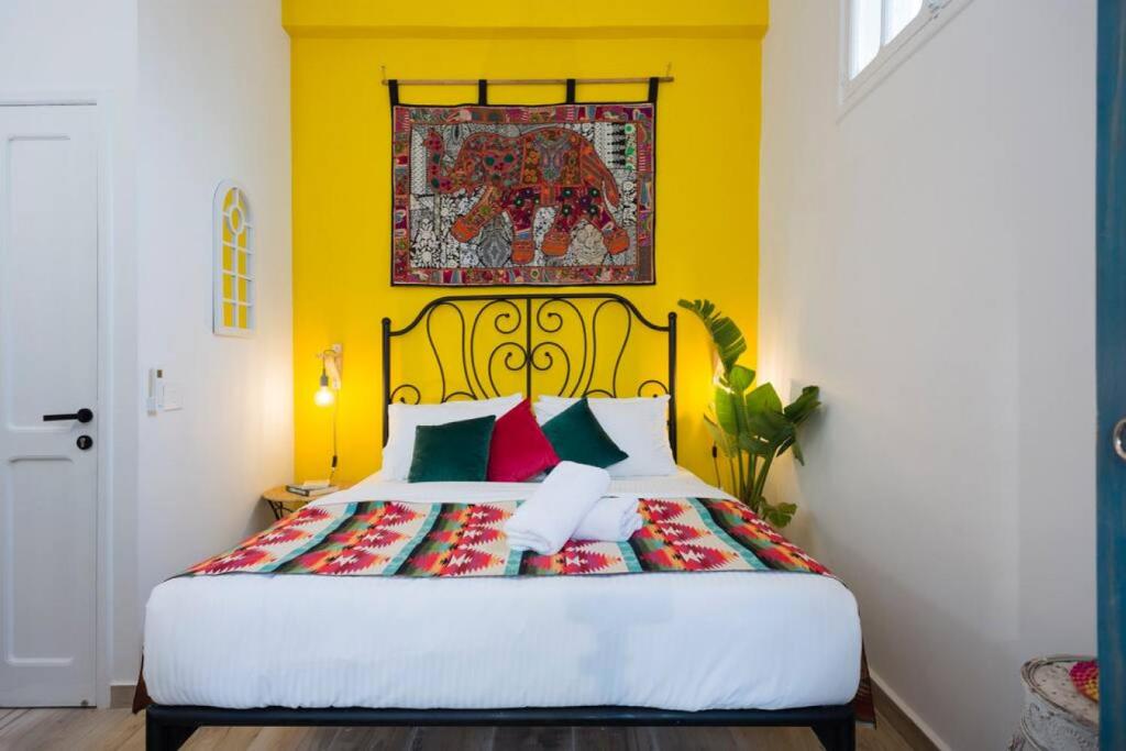 een slaapkamer met een bed met een gele muur bij Boho 03 Bohemian Studio in Mar Mikhael Eartha in Beiroet