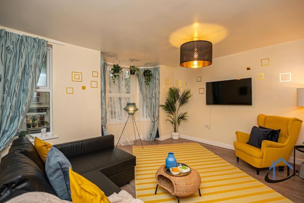 ein Wohnzimmer mit einem schwarzen Sofa und einem gelben Stuhl in der Unterkunft Sandby House, King beds workspace corporates parking sleeps 10 in Nottingham