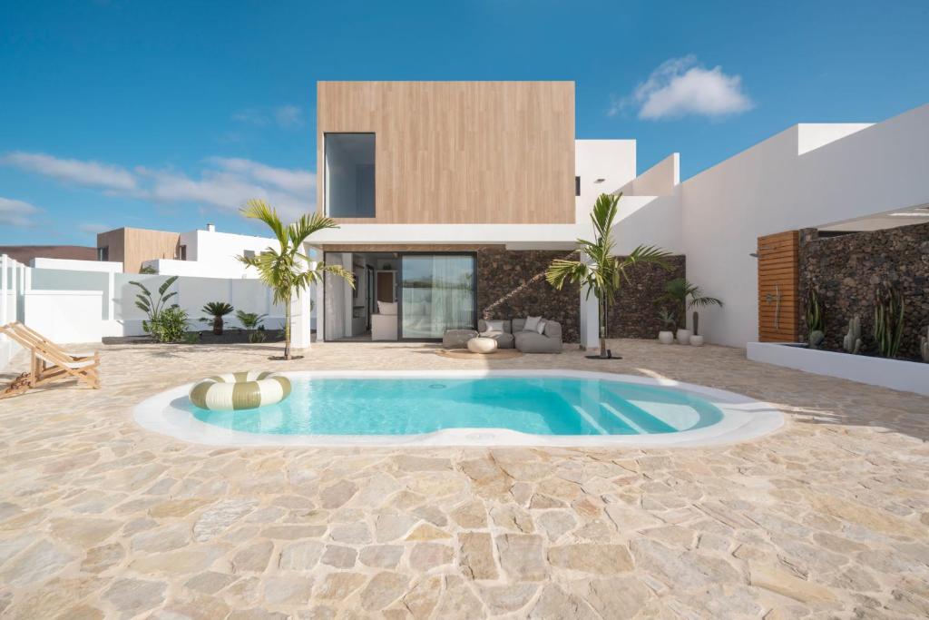 eine Villa mit einem Pool vor einem Haus in der Unterkunft Villa NOMA - Design space with Pool in Corralejo in Corralejo