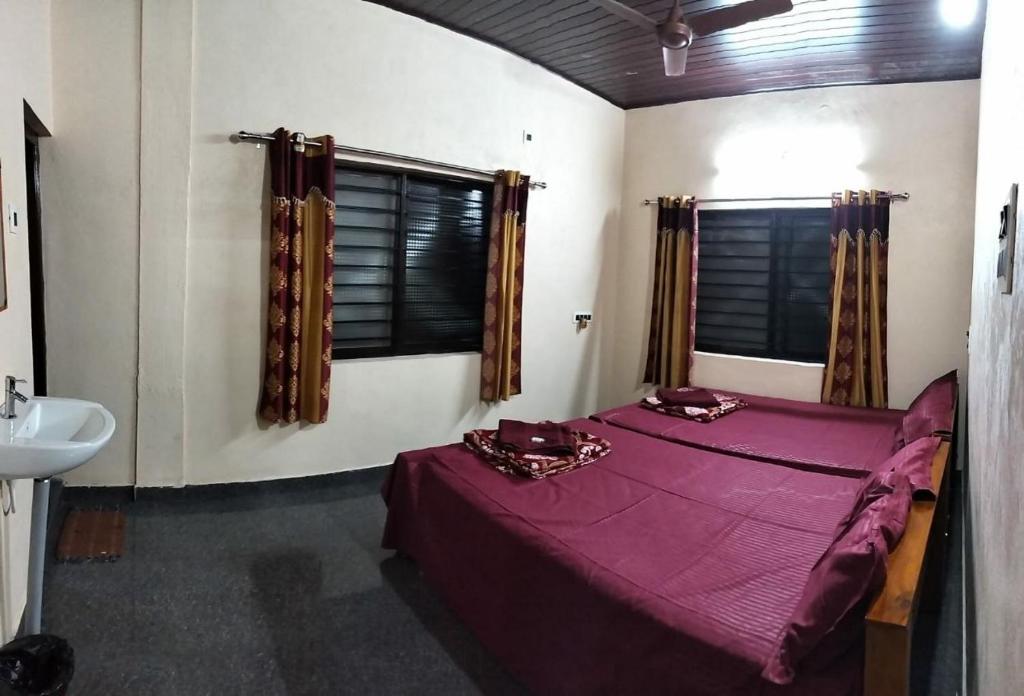1 dormitorio con cama morada y lavamanos en Aikya homestay, en Gokarna