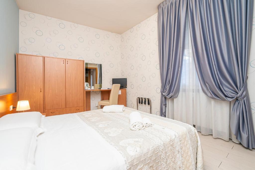 1 dormitorio con 1 cama grande con cortinas azules en Hotel Donatello en Bolonia