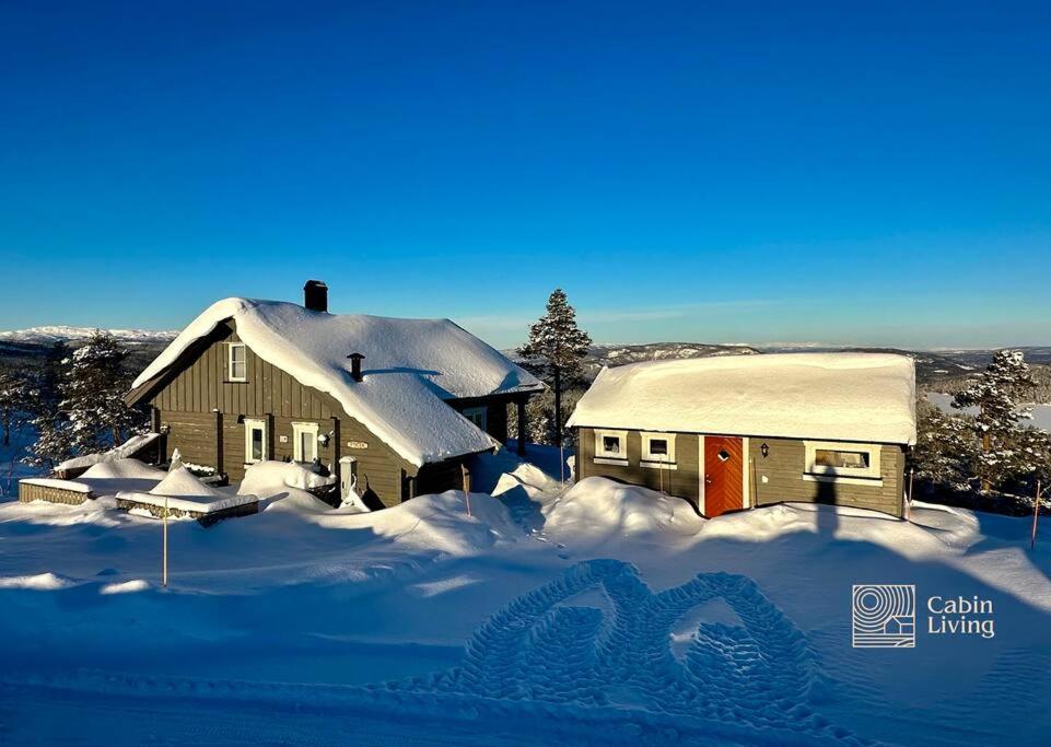 a house covered in snow in front at Cozy cabin with incredible views and sauna in Lampeland