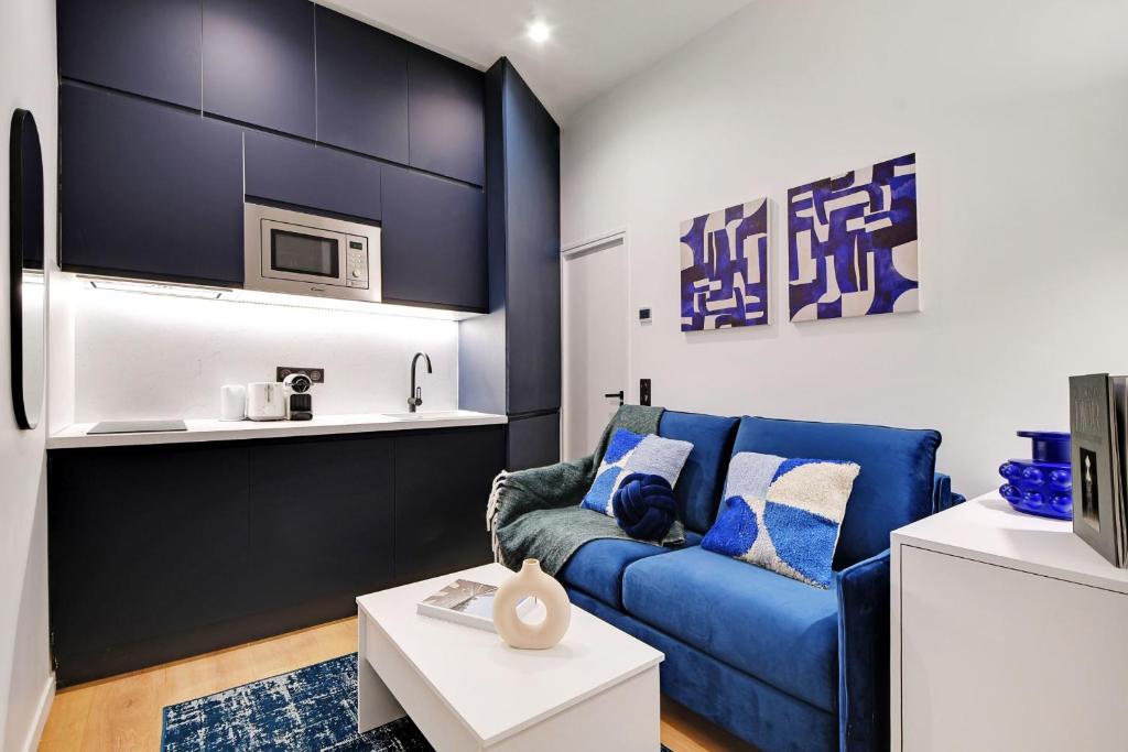 un salon avec un canapé bleu et un four micro-ondes dans l'établissement Intimate apartment - 1BR-2P - Parc des Princes, à Paris