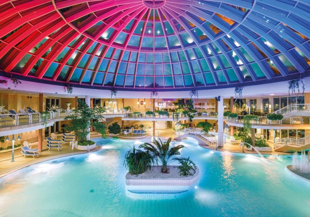 a large indoor pool in a building with a domed ceiling at Hotel Gran BelVeder in Scharbeutz