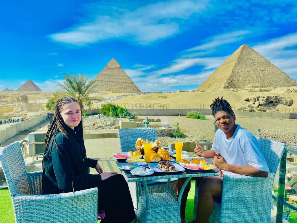 a man and woman sitting at a table in front of pyramids at Blue Scarab Pyramids View in Cairo