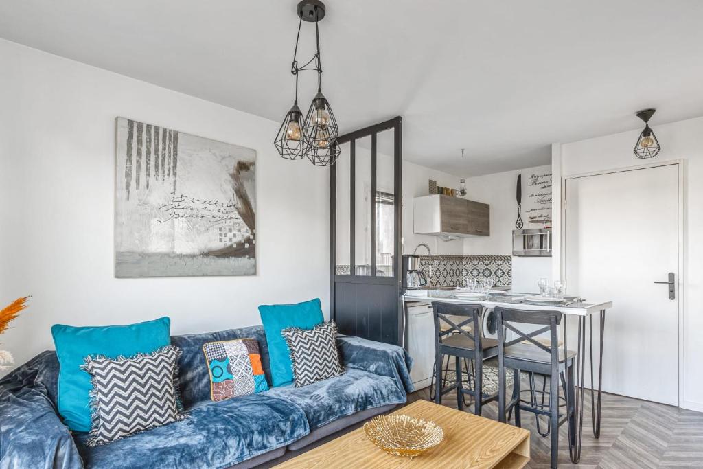 un salon avec un canapé bleu et une cuisine dans l'établissement Appartement Caima - Welkeys, à Cabourg