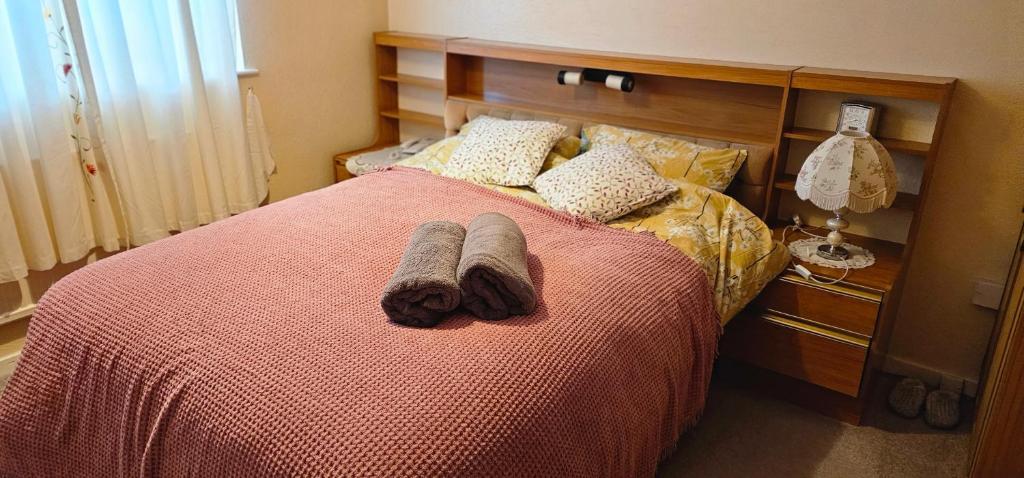 a bed with a red blanket and two towels on it at 2Bedroom Home away from Home in Manchester