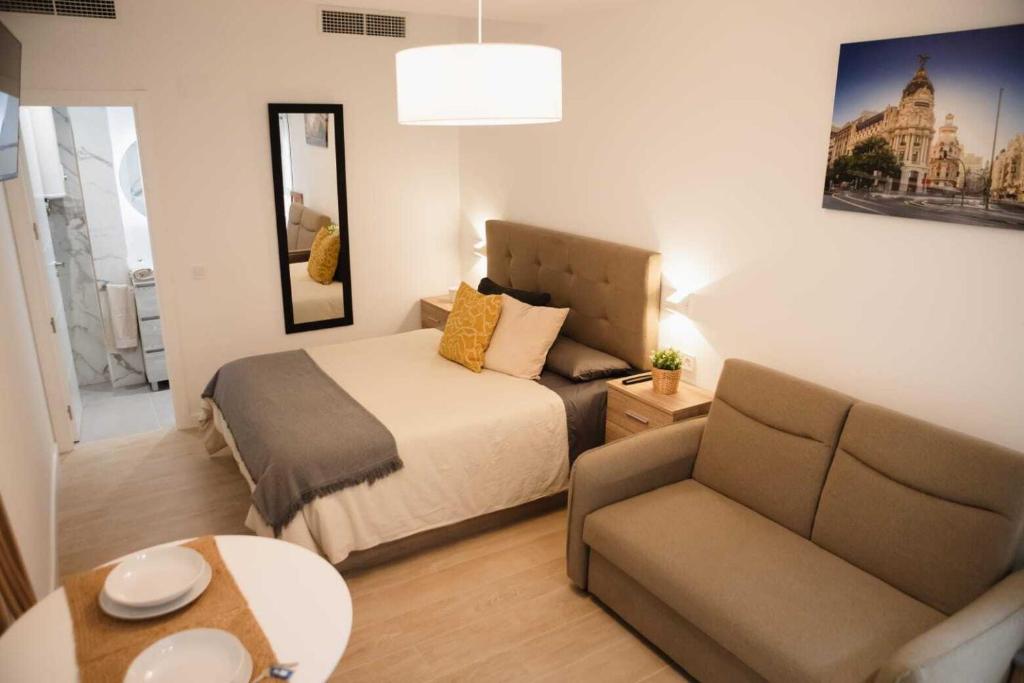 1 dormitorio con cama, sofá y mesa en Suits recién reformadas Marqués de Vadillo en Madrid