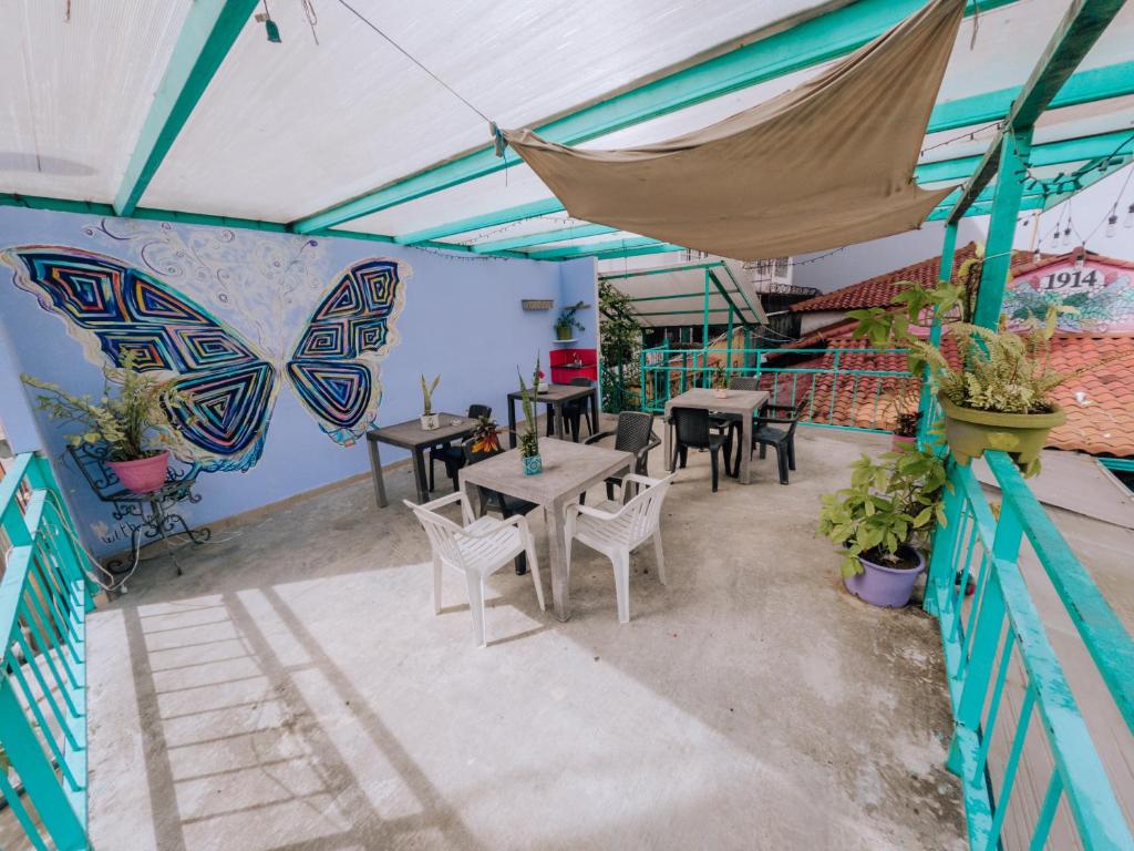 un patio avec des tables et des chaises et un papillon peint sur le mur. dans l'établissement Posada 1914, à Panama City