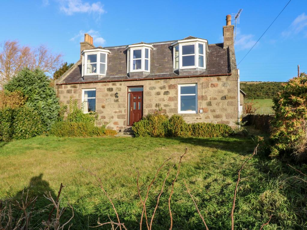 an old stone house on a grassy field at Wynford Holiday Cottage in Aberdeen