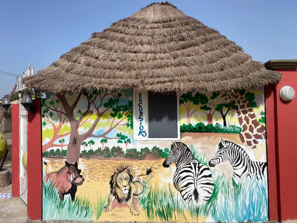 un bâtiment orné d'une peinture de zèbres et d'une girafe dans l'établissement La kora, à Toubakouta