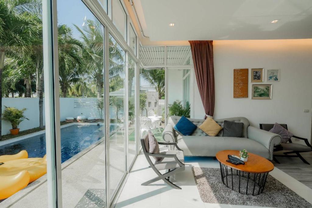 sala de estar con sofá, mesa y piscina en City Beach Cha-am Pool Villa en Cha Am