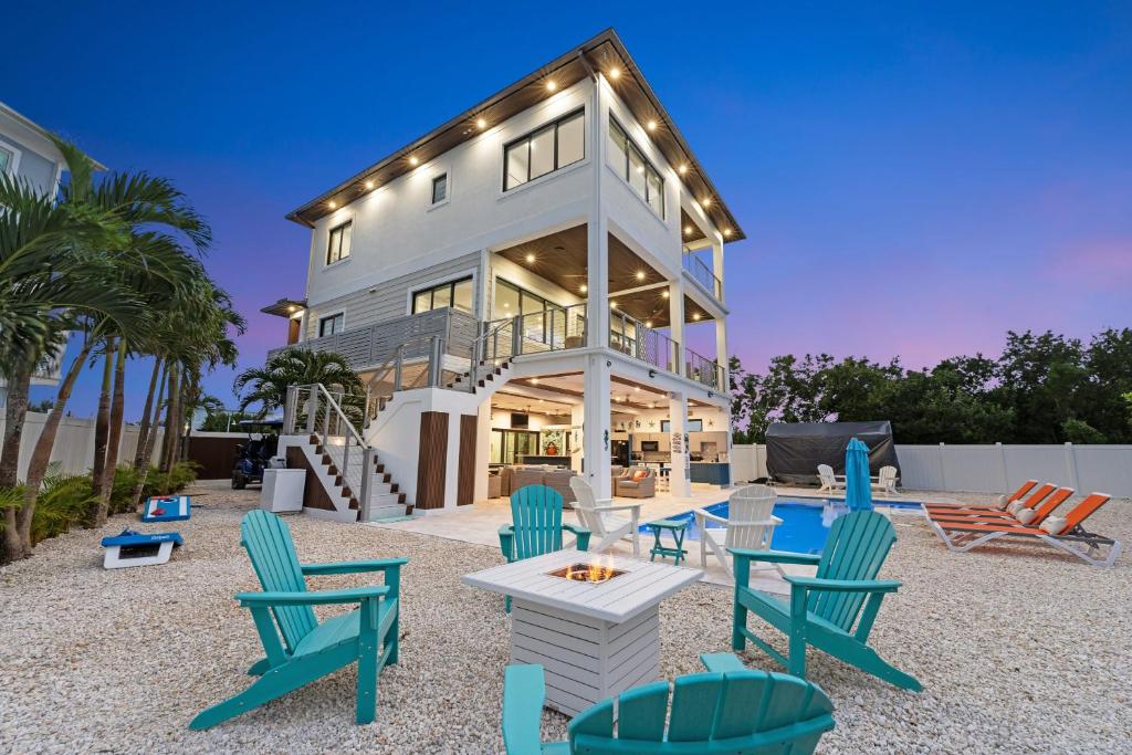 马拉松Luxury Seaside Escape ~ Heated Pool w Jacuzzi ~ Elevator ~ Dock ~ Scenic Views的房屋前面设有桌椅
