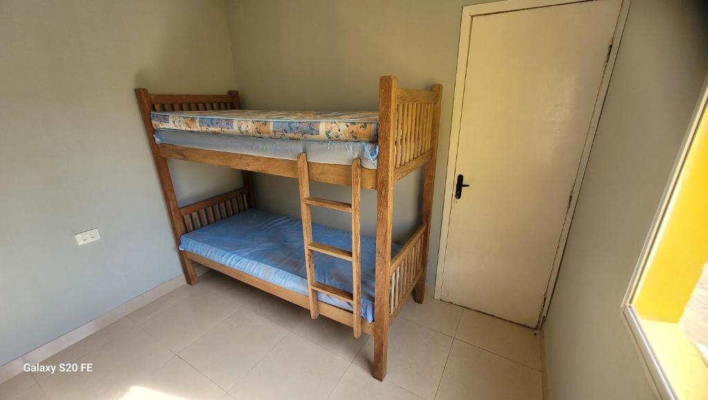2 Etagenbetten in einem kleinen Zimmer mit einer Tür in der Unterkunft Casado mar in Tamandaré