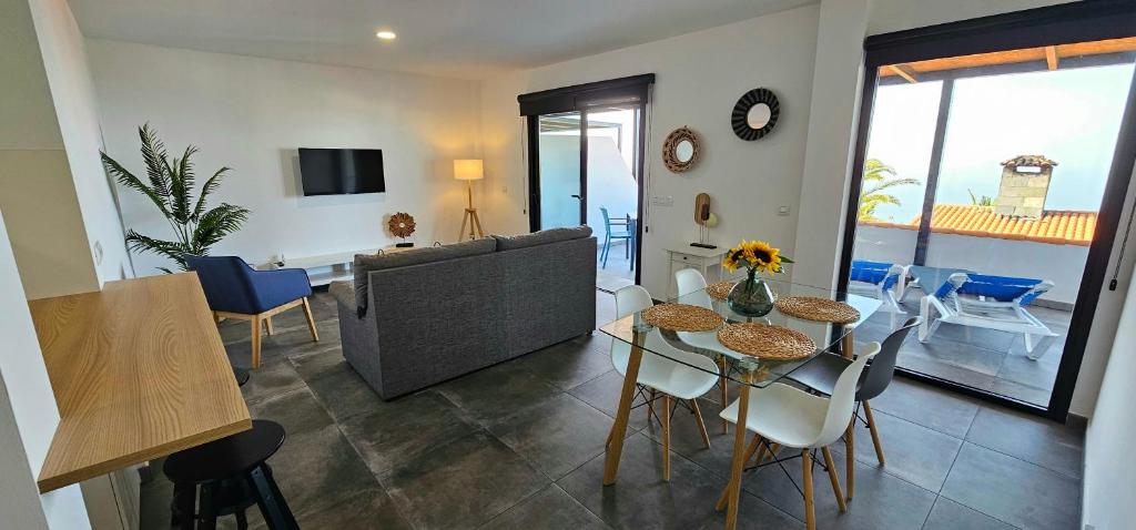 een woonkamer met een bank en een tafel en stoelen bij Las Norias Apartamentos & Grill in Tazacorte