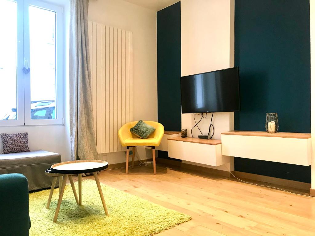 d'un salon avec une télévision et une chaise jaune. dans l'établissement Adorable souplex batignolles, à Paris